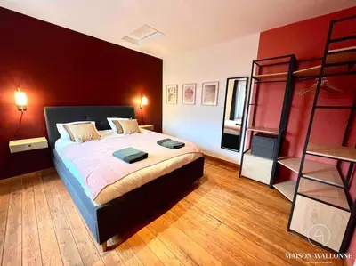 a bedroom with a large bed with a red wall at Le Loft liégeois - Au coeur de la cité in Liège