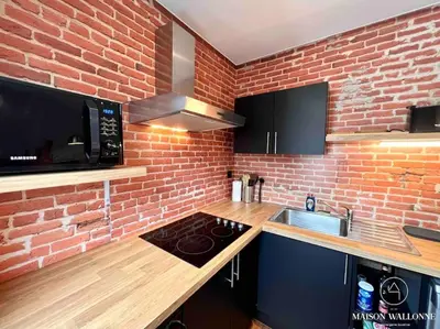 a kitchen with a brick wall and a stove top oven at Le Loft liégeois - Au coeur de la cité in Liège
