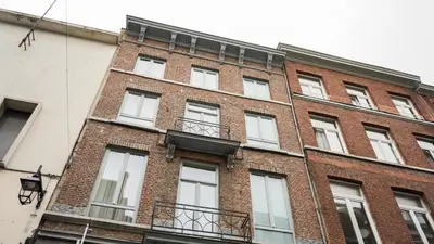 a red brick building with white windows on it at Amosa Liège City Centre Hotel in Liège