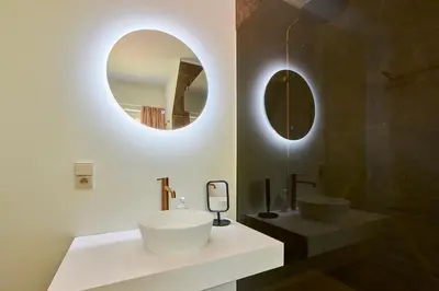 a bathroom with a white sink and two mirrors at Villa Bosrijk in Lommel