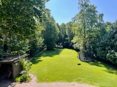 a large green yard with a bench and trees at Villa Bosrijk in Lommel