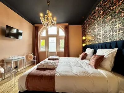 a bedroom with a large bed and a chandelier at Maison du Roi in Liège