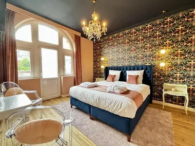 a bedroom with a blue bed in a room with a wall covered in vines at Maison du Roi in Liège