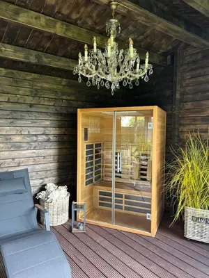a chandelier hanging from a wooden house with a porch at Maison Idyllique in Bree