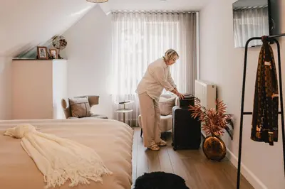 a woman standing in a bedroom with a suitcase at Maison Idyllique in Bree