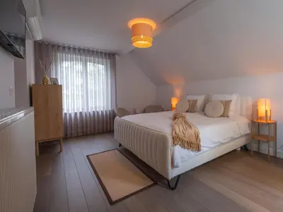 a bedroom with a large white bed and a window at Maison Idyllique in Bree