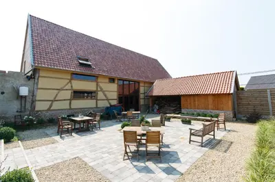 a patio with tables and chairs in front of a building at Apartment 't Maanhof in Gingelom