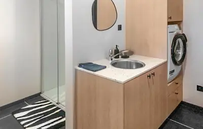 a bathroom with a sink and a washing machine at Looshof in Helchteren