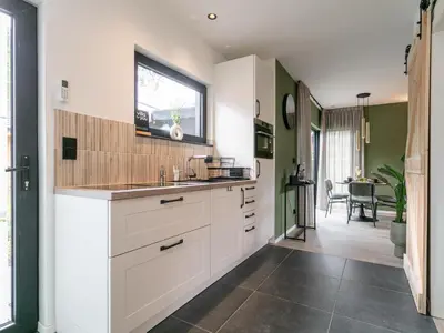 a kitchen with white cabinets and a window at Thalor in Zutendaal
