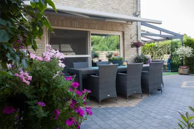 a patio with a table and chairs and flowers at B&B De Watering in Lommel