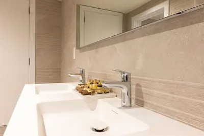 a bathroom sink with two faucets and a mirror at Stijlvol appartement met jacuzzi & sauna in Herk-de-Stad