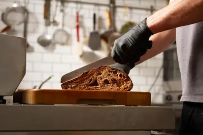 a person cutting a loaf of bread with a knife at Hotel Het Menneke in Hasselt