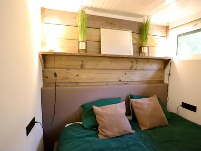 a bed in a room with two plants on a wall at Sonnig Bungalow in Lanaken