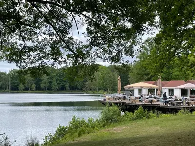 a dock with tables and chairs next to a lake at Lacuna VITA by Sonnevijver Residences in Lanaken