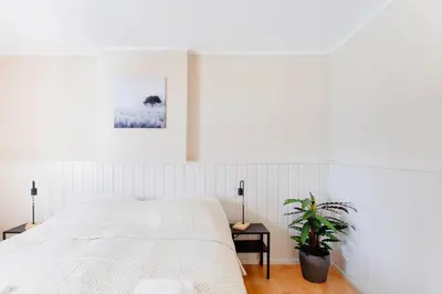 a white bedroom with a bed and a potted plant at 8P 4B Authentic house with playroom and infrared sauna in Bilzen