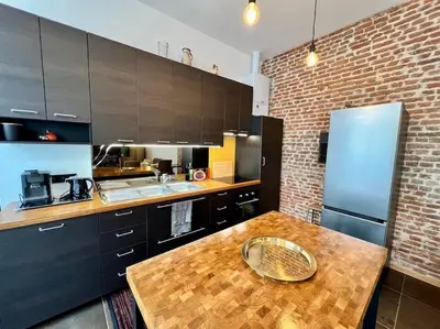 a kitchen with a wooden table and a brick wall at Art Loft -Opéra, Saint-Lambert, Bueren in Liège