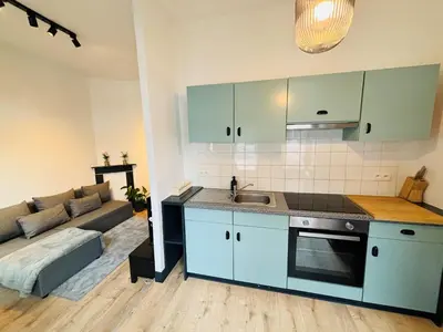 a kitchen with blue cabinets and a living room at Appartement Cosy Liège Station in Liège