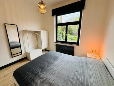 a bedroom with a large bed and a window at Appartement Cosy Liège Station in Liège