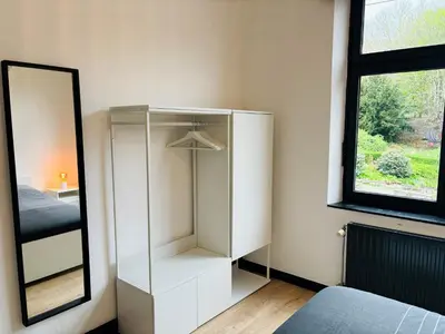 a white cabinet in a bedroom with a mirror at Appartement Cosy Liège Station in Liège