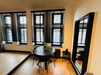 a dining room with a table and some windows at Appartement Cosy Liège Station in Liège
