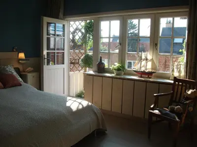 a bedroom with a bed and windows and a chair at Apartment Het Demerhuisje in Hasselt