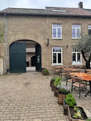 a brick building with tables and benches in front of it at Luxe in Het Posthuis - nieuwe Stijlvolle Verblijven in Oud-Rekem in Lanaken