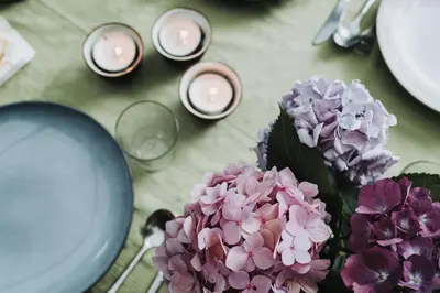 a table topped with purple flowers and candles at Huisje Mezengroet in Lanaken