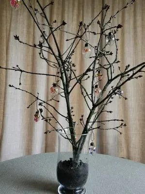 a vase with branches and ornaments on a table at Huisje Mezengroet in Lanaken