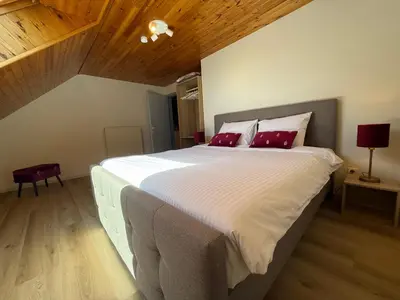 a bedroom with a large white bed with red pillows at Villa Luna in Oudsbergen