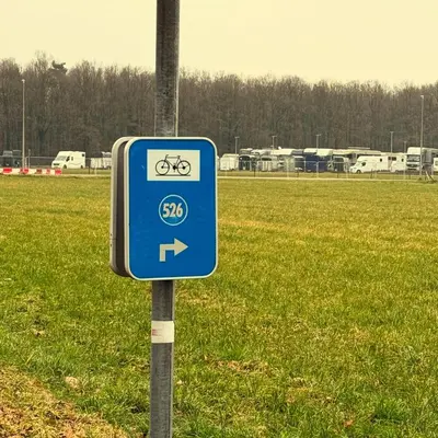 a blue bike sign on a pole in a field at Villa Luna in Oudsbergen