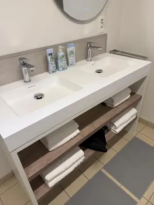 a bathroom sink with two faucets and towels at Villa Luna in Oudsbergen