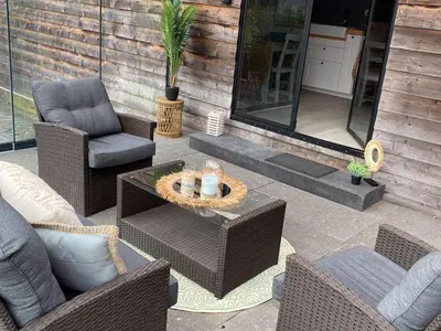 a patio with wicker chairs and a table with candles at Chalet Wielsmer in Zutendaal