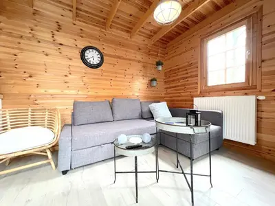 a living room with a couch and a clock on the wall at Chalet Wielsmer in Zutendaal