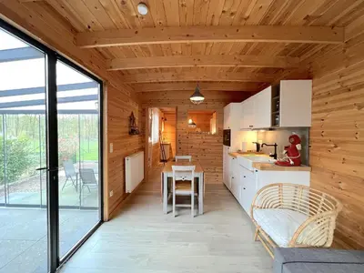 a kitchen with wooden walls and a large window at Chalet Wielsmer in Zutendaal