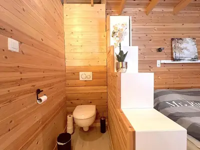 a bathroom with wooden walls and a toilet in a room at Chalet Wielsmer in Zutendaal