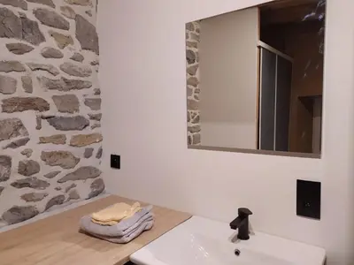 a bathroom with a sink and a stone wall at Close from Ardenne - Fully renovated modern farmhouse in Baelen in Baelen