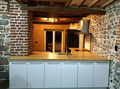 a kitchen with white cabinets and a brick wall at Close from Ardenne - Fully renovated modern farmhouse in Baelen in Baelen