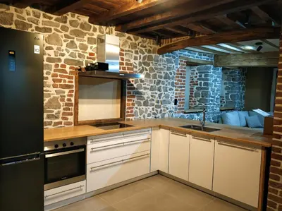 a kitchen with white cabinets and a stone wall at Close from Ardenne - Fully renovated modern farmhouse in Baelen in Baelen