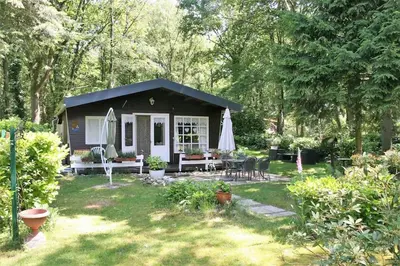 a small shed with a table and chairs in a yard at Vakantie Bos Huisje “Meibloempje” in Lanaken