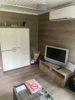 a living room with a flat screen tv and a cabinet at Vakantie Bos Huisje “Meibloempje” in Lanaken