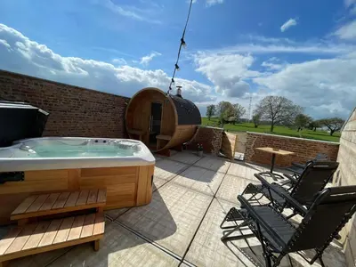 a hot tub on a patio with two chairs at Boven de paarden @ de Hoeveschuur in Riemst