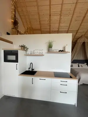 a kitchen with white cabinets and a sink and a bed at Boven de paarden @ de Hoeveschuur in Riemst