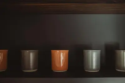 a row of different colored cups sitting on a shelf at L’exclusif in Aubel