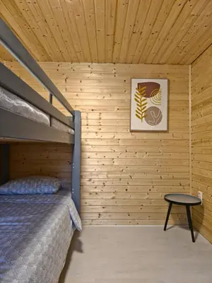 a bedroom with a bunk bed in a wooden wall at Cozychalet met prive Hot tub in Lanaken