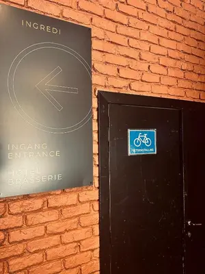 a sign on a brick wall next to a black door at Hotel INGREDI in Bree