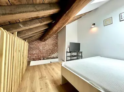a bedroom with a bed and a brick wall at Le Belvédère de la Rose-Hors château, hypercentre in Liège