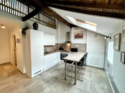 a kitchen with white cabinets and a wooden table at Le Belvédère de la Rose-Hors château, hypercentre in Liège