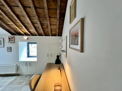a dining room with a wooden table and white walls at Le Belvédère de la Rose-Hors château, hypercentre in Liège