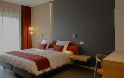 a bedroom with a large bed with red pillows at Hôtel Les Fines Gueules in Herve