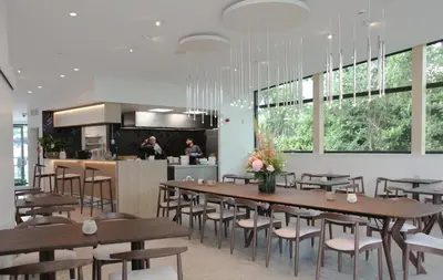 a restaurant with wooden tables and chairs and a kitchen at Hôtel Les Fines Gueules in Herve